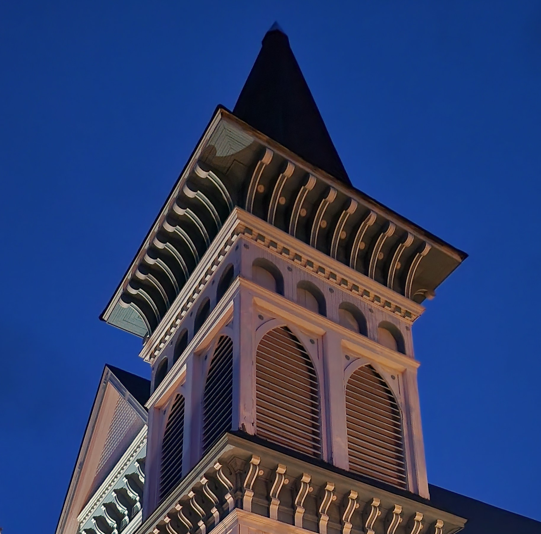 An ornamented wooden church steeple with nighttime skies around it.