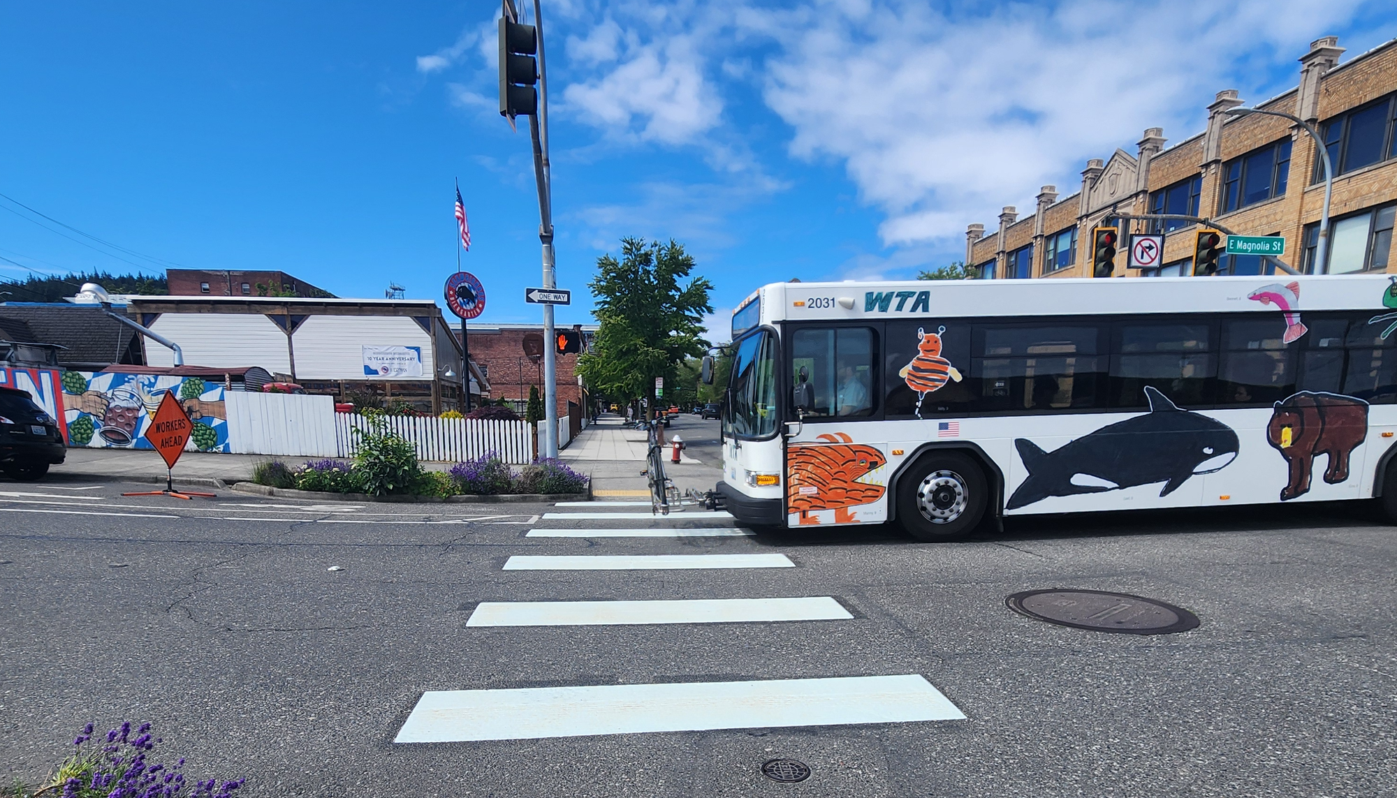 A bus wrapped in kids art passes through an intersection.