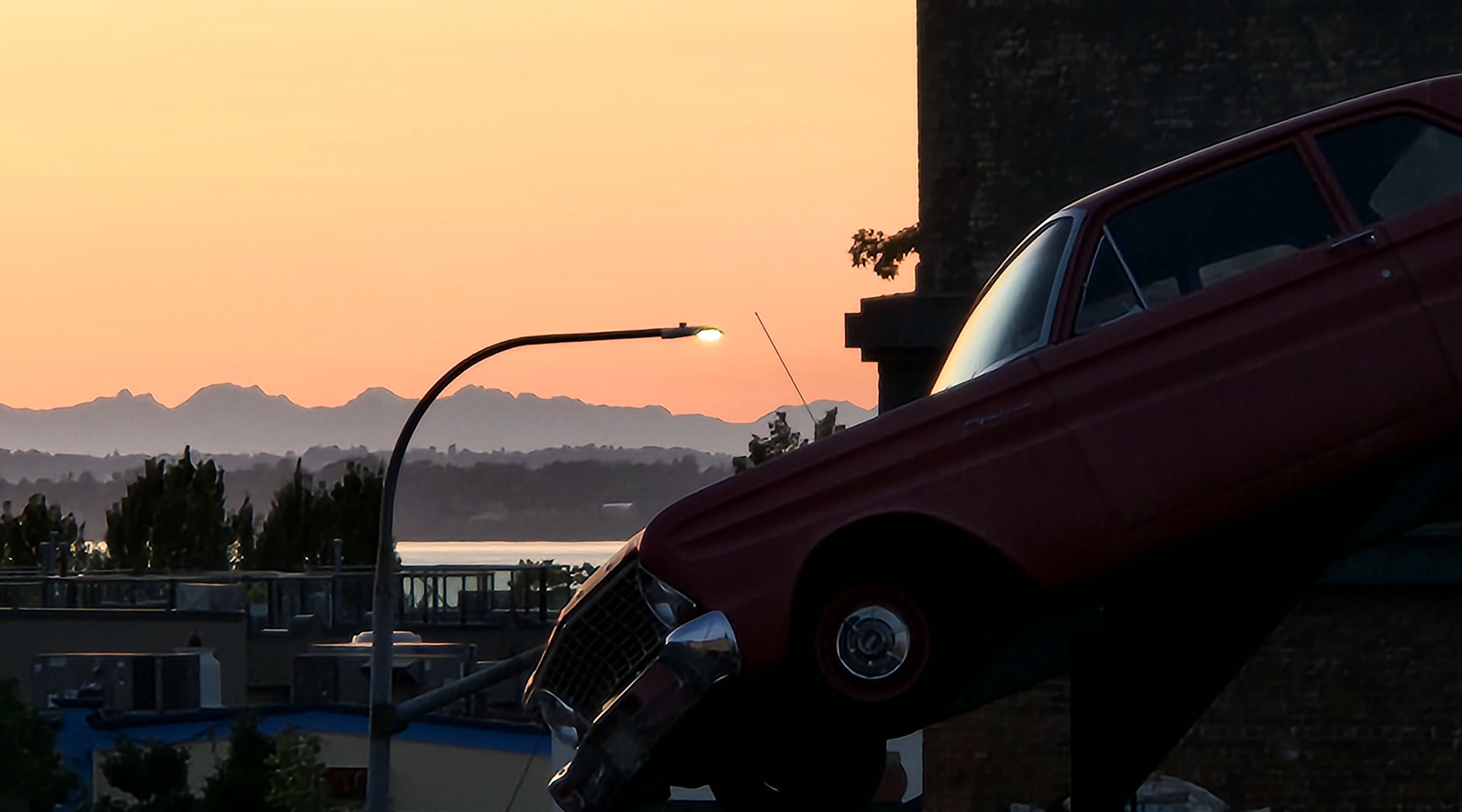 A photo of mountains in the distance at subset with a 1950s vintage car in the foreground.