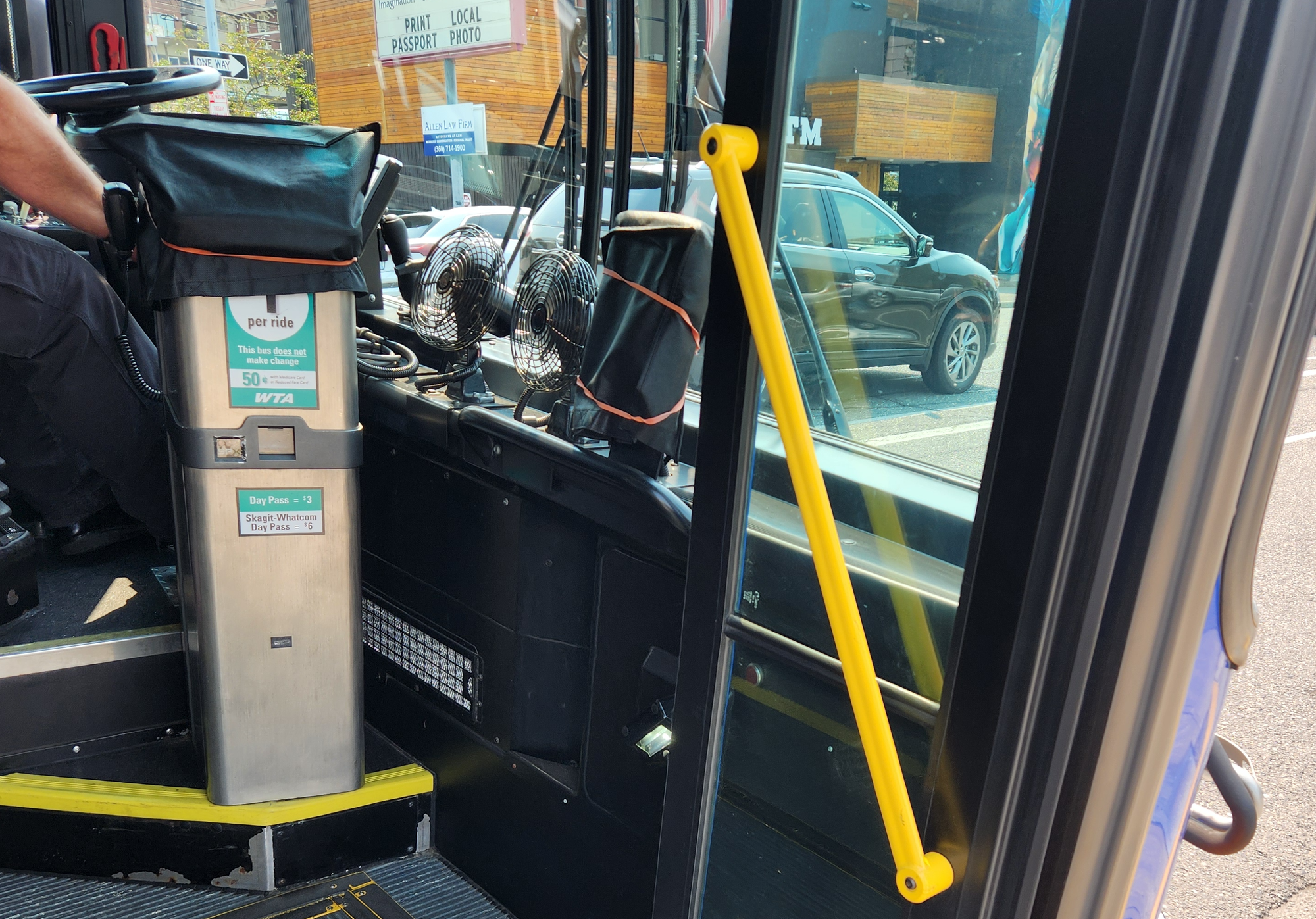 At a bus entry point, a farebox machine and pass validator are covered up in a black tarp. 